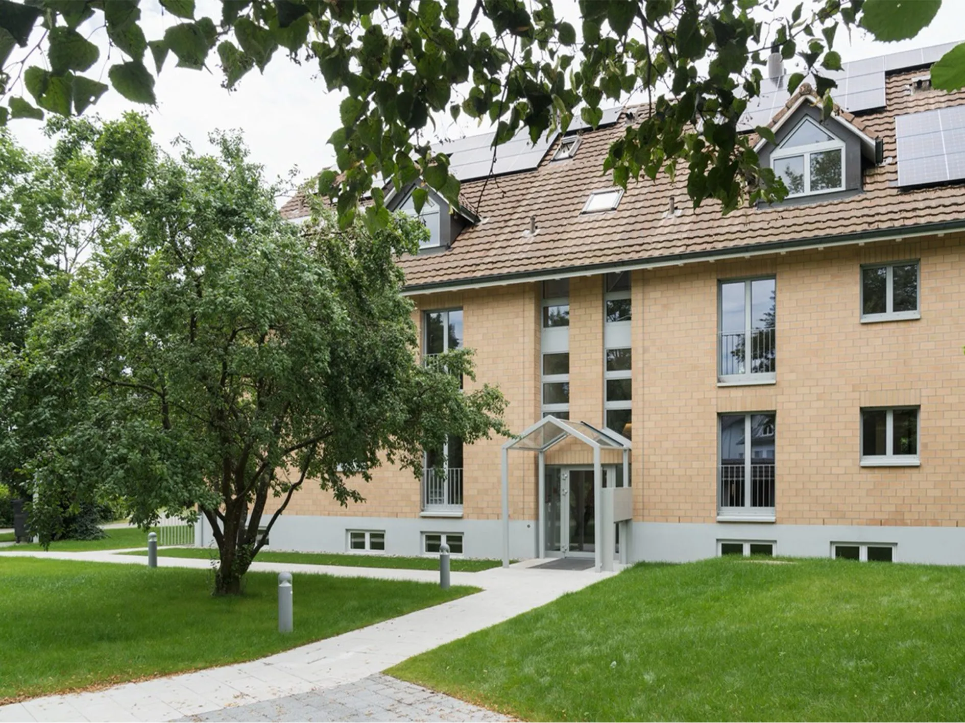 Fertiggestelltes Mehrfamilienhaus mit Eingang und Garten